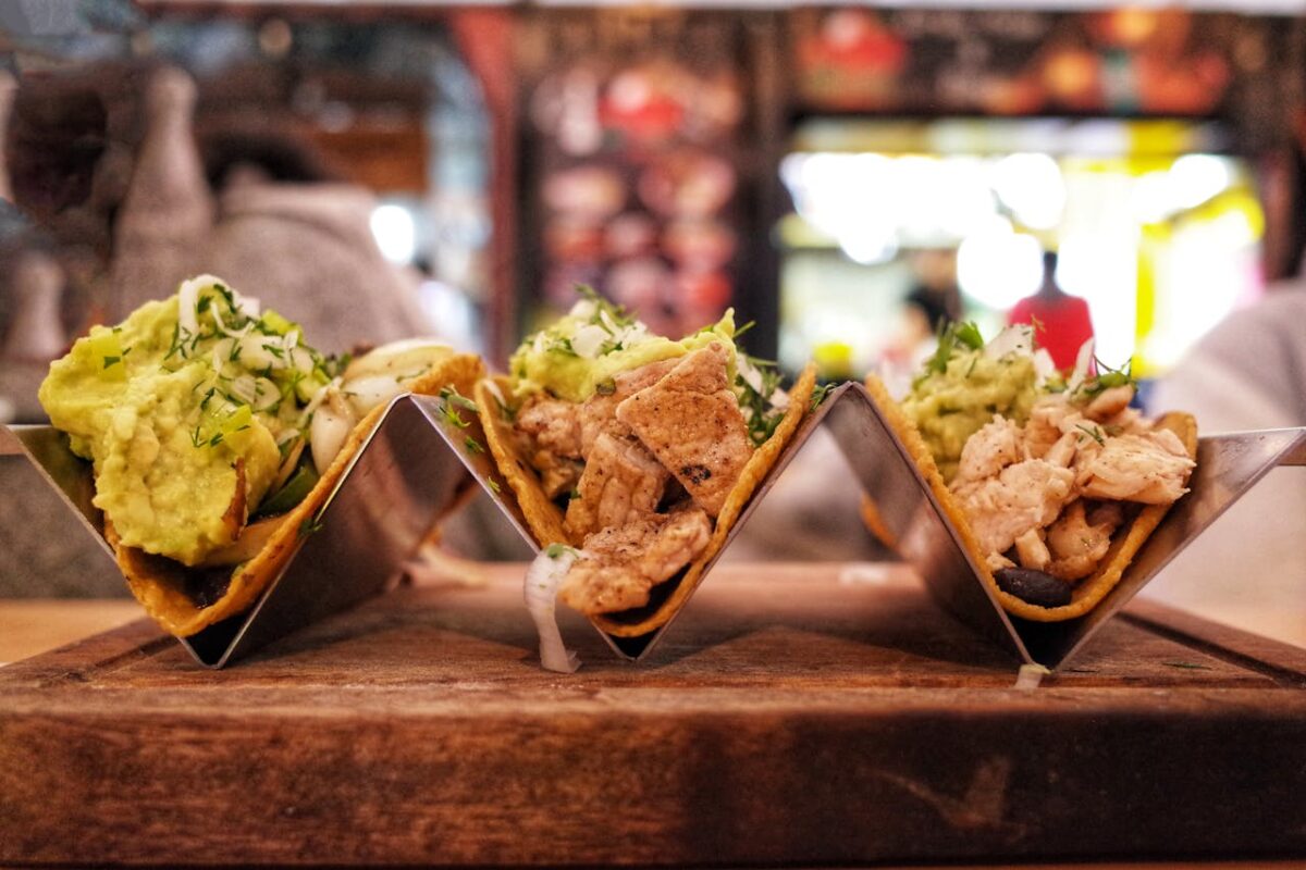 portfolio-06 Close-up of delicious chicken tacos with avocado, served in a modern restaurant setting.