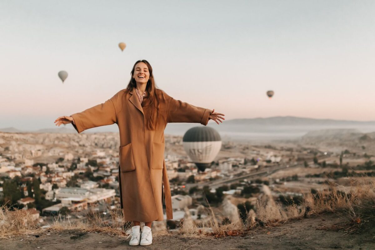 why-choose-us Woman enjoying sunrise with hot air balloons over Cappadocia.